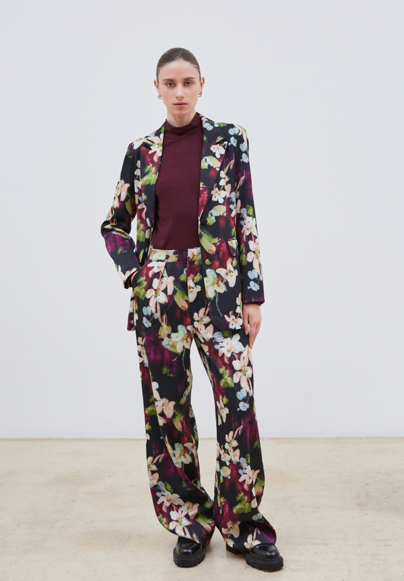 Le pantalon Flora séduit par son motif floral délicat aux nuances de mauve, bleu ciel, vert clair et beige, posé sur un fond noir élégant. Confectionné dans un tissu de qualité, il assure une allure chic et sophistiquée. Polyvalent, il s’adapte parfaitement porté seul ou accompagné de son blazer assorti, pour un ensemble harmonieux et raffiné.
